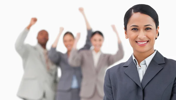 Smiling saleswoman with cheering colleagues behind her — Stock Photo, Image