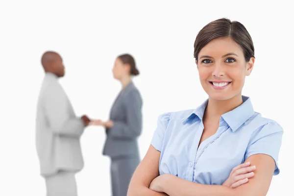 Smiling businesswoman with arms crossed and colleagues behind he — Stock Photo, Image