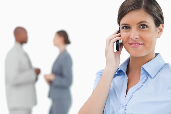 Tradeswoman with mobile phone and associates behind her — Stock Photo, Image