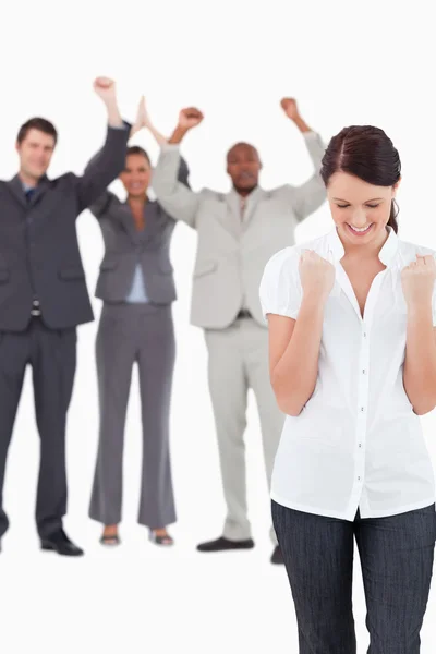 Triumphant businesswoman with cheering colleagues behind her — Stock Photo, Image