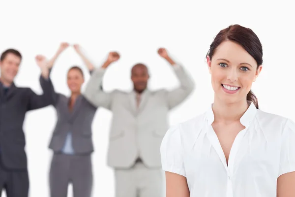 Smiling saleswoman with cheering associates behind her — Stock Photo, Image