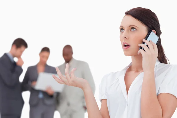 Vendedora falando ao telefone com colegas por trás dela — Fotografia de Stock