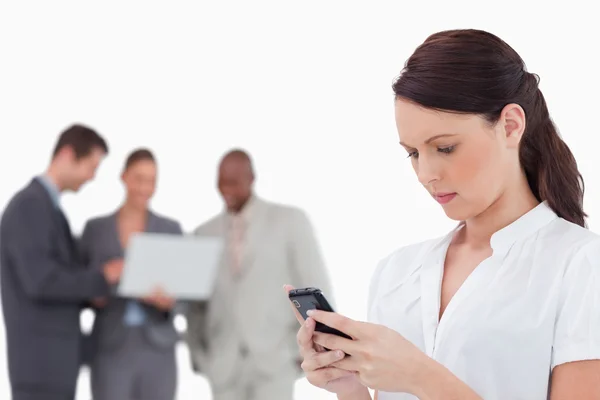 Försäljare läser textmeddelande med kollegor bakom henne — Stockfoto