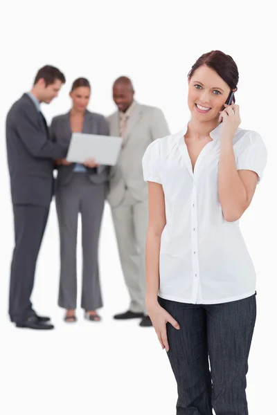 Saleswoman with associates behind her on the phone — Stock Photo, Image