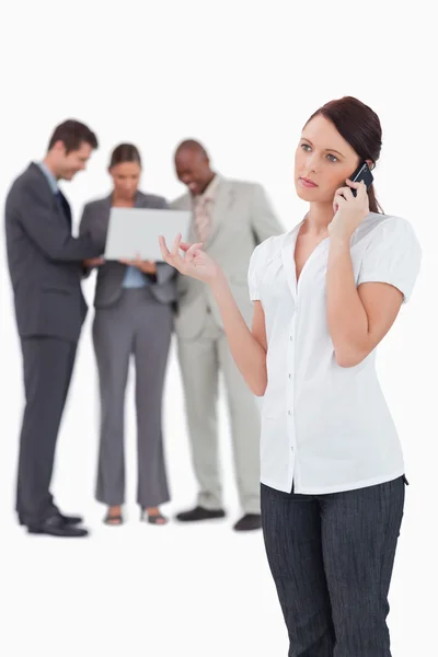 Businesswoman on the phone with colleagues behind her — Stock Photo, Image