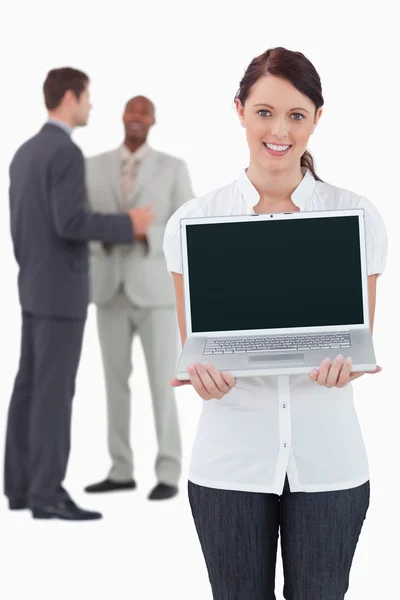 Üzletasszony mutatja a kollégákkal, háta mögött laptop — Stock Fotó