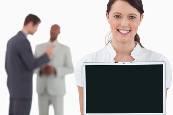 Tradeswoman showing laptop with colleagues behind her — Stock Photo, Image