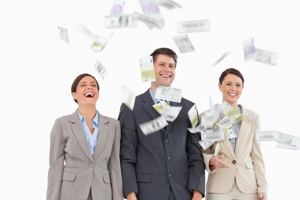 Pengar som faller ner på leende businessteam — Stockfoto