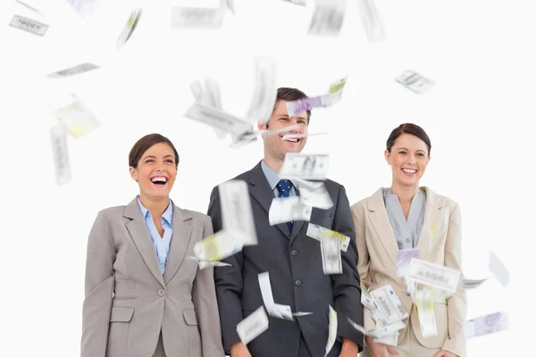 Pengar sjunker ner på leende businessteam — Stockfoto