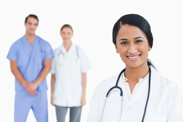 Sorridente medico con i colleghi dietro di lei — Foto Stock