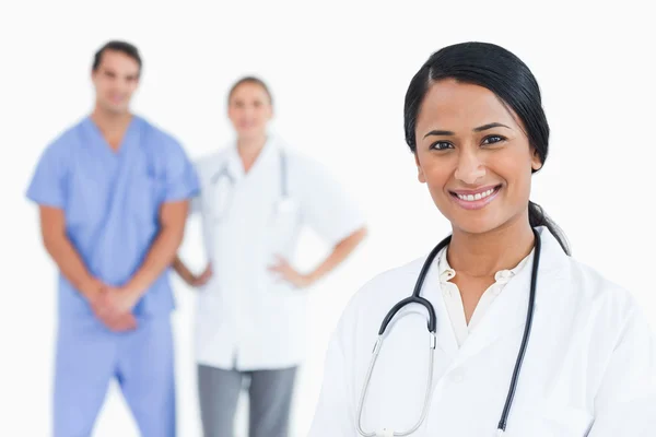 Sorridente medico femminile con i colleghi dietro di lei — Foto Stock
