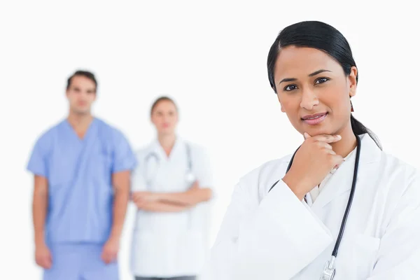 Thoughtful doctor with colleagues behind her — Stock Photo, Image