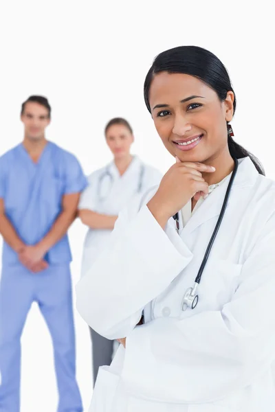 Uśmiechający się lekarz z pracowników za nią — Zdjęcie stockowe