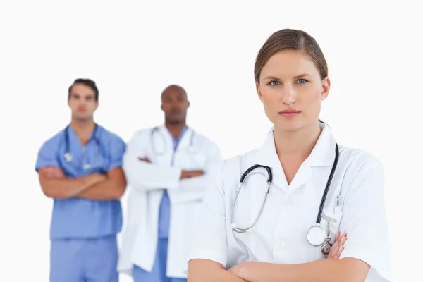 Vrouwelijke arts met gevouwen armen en mannelijke collega's achter haar — Stockfoto