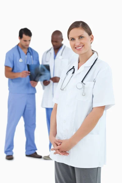 Medico sorridente con colleghi e radiografie dietro di lei — Foto Stock