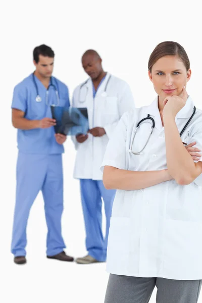 Médico pensante con colegas detrás de ella —  Fotos de Stock
