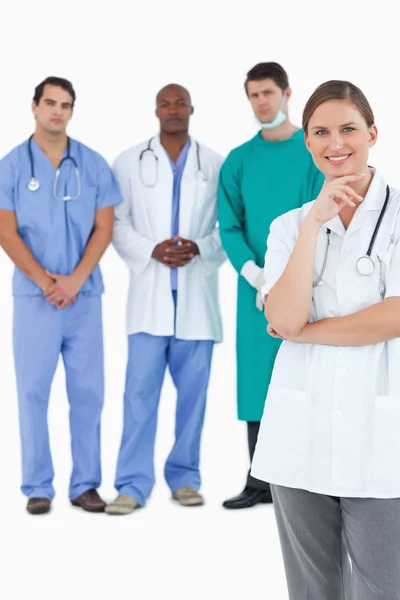 Улыбающийся доктор с работниками мужского пола позади нее — стоковое фото