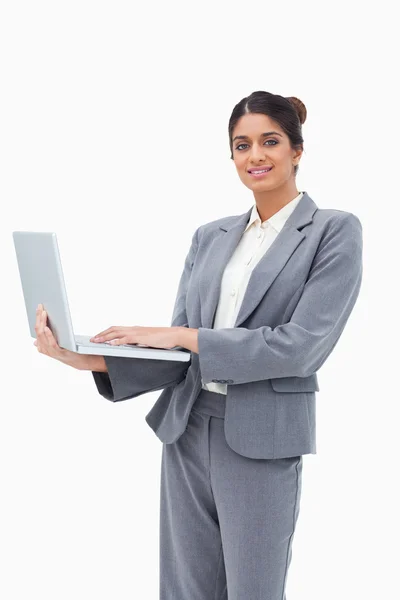 Empresária sorridente usando notebook enquanto está de pé — Fotografia de Stock