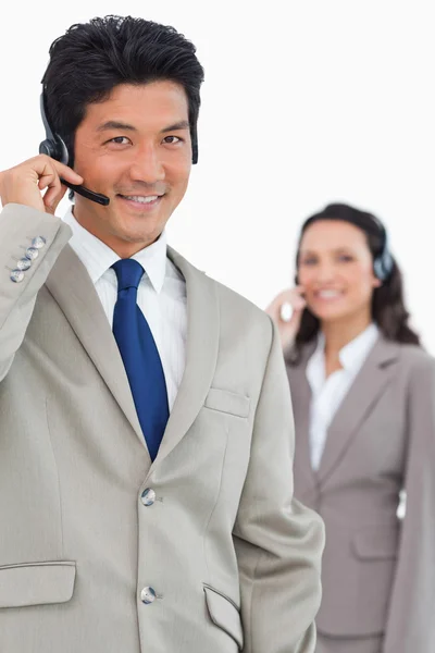 Sorrindo empregado de suporte ao cliente com colega atrás dele — Fotografia de Stock