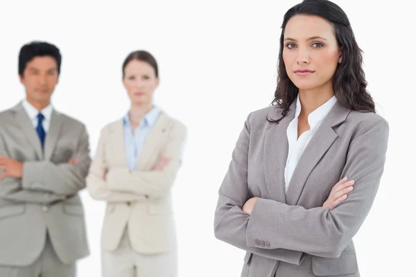 Confident saleswoman with arms folded and colleagues behind her — Stock Photo, Image