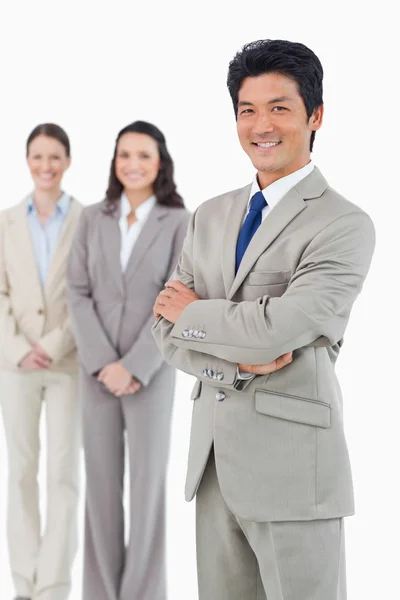 Vertrouwen lachende zakenman met zijn werknemers achter hem — Stockfoto
