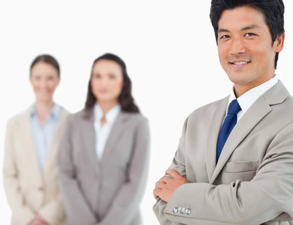 Smiling young businessman with colleagues behind him — Stock Photo, Image