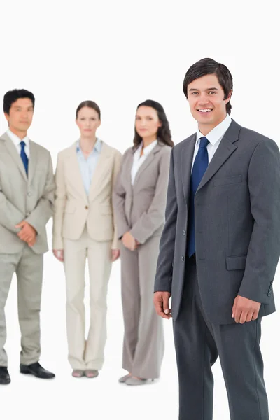Smiling young salesman with team behind him — Stock Photo, Image