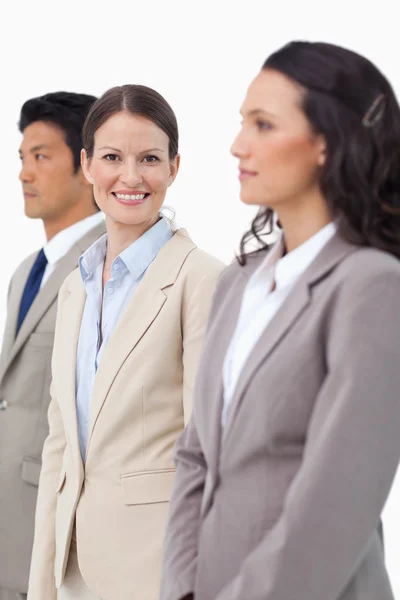 Smiling saleswoman standing between colleagues — Stock Photo, Image