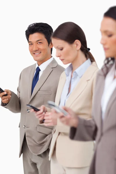 Smiling businessman with cellphone next to colleagues — Stock Photo, Image