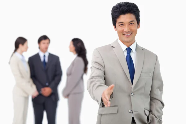 Businessman with colleagues behind him offering his hand — Stock Photo, Image