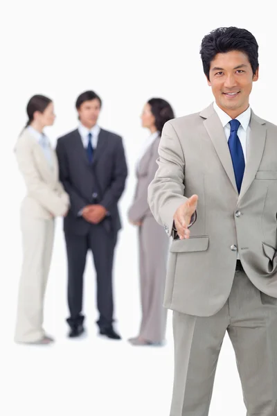 Businessman with colleagues behind him extending his hand — Stock Photo, Image