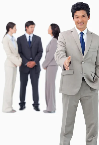 Businessman with team behind him offering hand — Stock Photo, Image