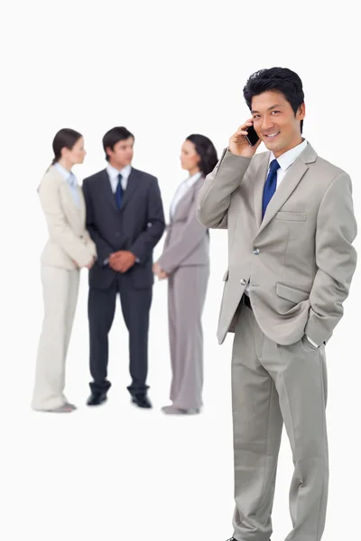 Empresário no celular com colegas atrás dele — Fotografia de Stock
