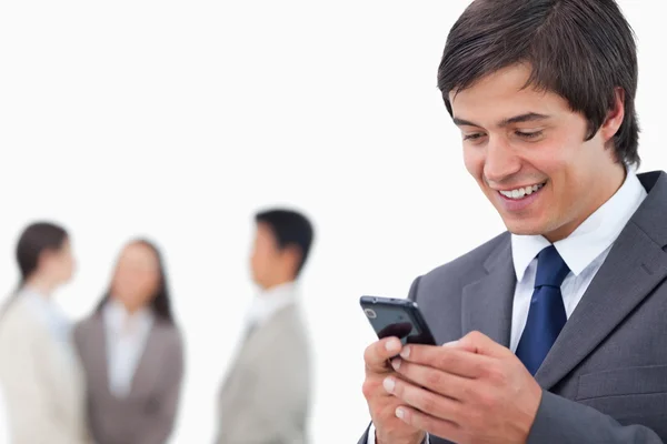 Salesman writing text message with team behind him — Stock Photo, Image