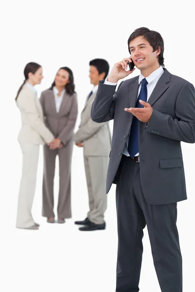 Handelaar praten over de telefoon met team achter hem — Stockfoto