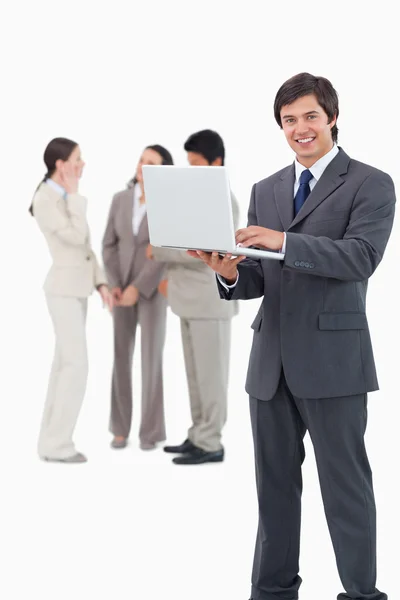 ノート パソコンと彼の背後にあるチームと笑みを浮かべてセールスマン — ストック写真