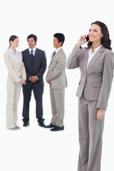 Saleswoman on the cellphone with team behind her — Stock Photo, Image