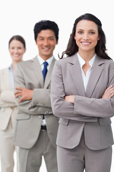 Smiling businesswoman with team and folded arms — Stock Photo, Image