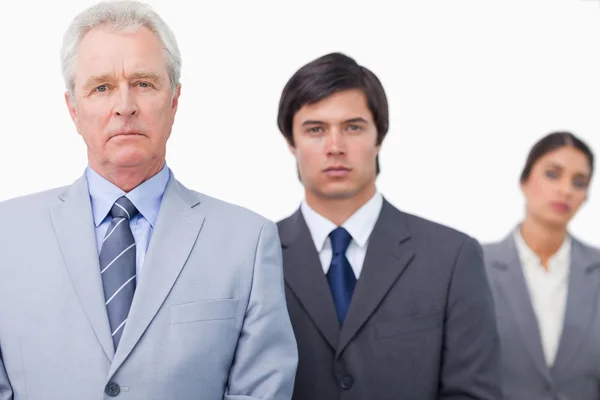 Mature salesman standing with employees — Stock Photo, Image