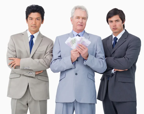 Starszy biznesmen z pieniędzy stojący między jego pracowników — Zdjęcie stockowe