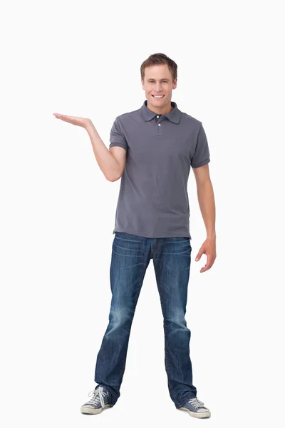 Lächelnder junger Mann präsentiert mit erhobener Handfläche — Stockfoto