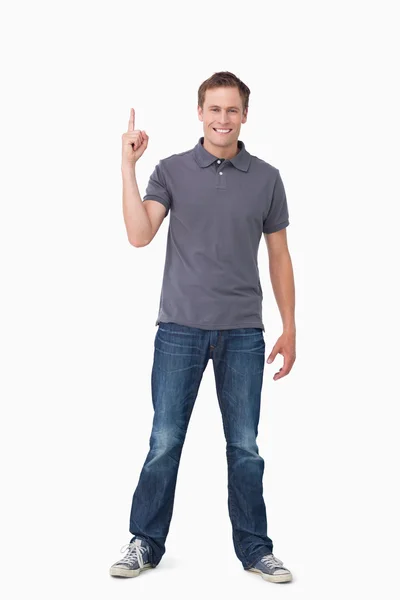 Lächelnder junger Mann zeigt nach oben — Stockfoto