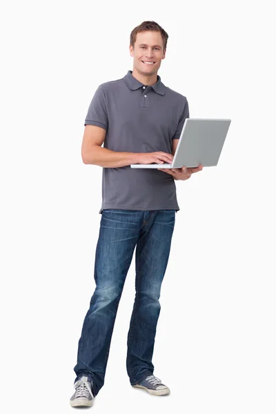 Lachende jonge man aan het werk op zijn laptop — Stockfoto