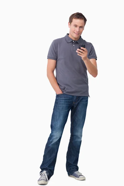 Junger Mann hält sein Handy — Stockfoto