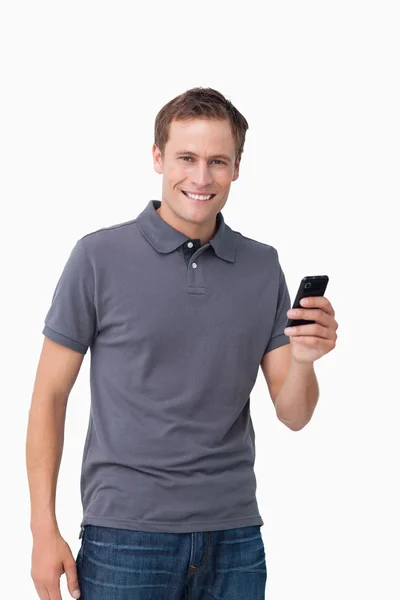 Joven sonriente sosteniendo su celular — Foto de Stock