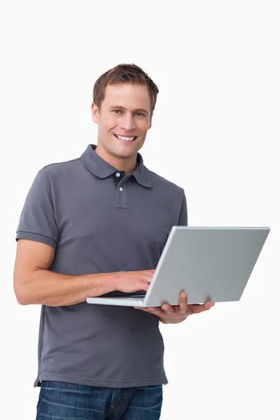 Lächelnder junger Mann mit seinem Laptop — Stockfoto