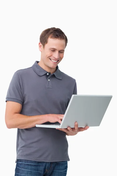 Улыбающийся молодой человек, работающий на ноутбуке — стоковое фото