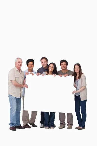 Smiling group of friends holding blank sign together — Stock Photo, Image