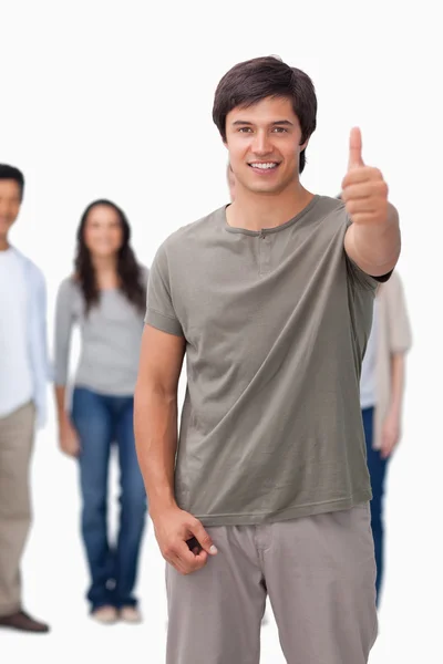 Smiling man giving thumb up with friends behind him — Stock Photo, Image