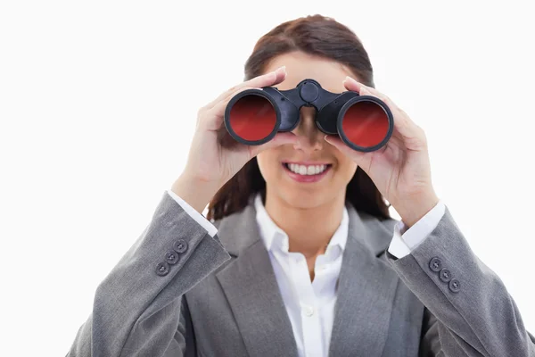 Businesswoman smiling and looking through binoculars — Stock Photo, Image